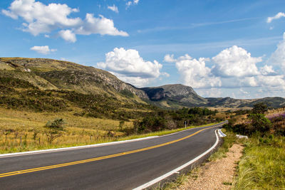 Road leading towards mountains against sky