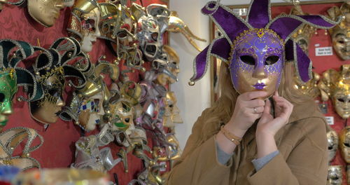 Portrait of woman holding mask hanging