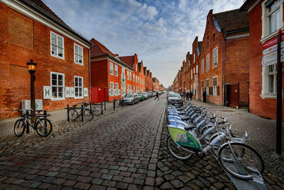 Bicycles on street amidst buildings against sky in city