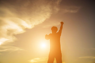 Rear view of silhouette man standing against sky during sunset