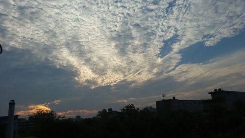 Low angle view of silhouette building against cloudy sky