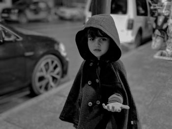 Portrait of boy standing on street in city