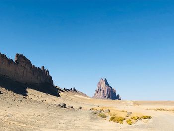 Panoramic view of arid landscape against clear blue sky