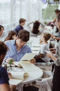 Female owner taking order from male customer sitting in restaurant