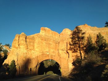 Road amidst rocks against clear blue sky