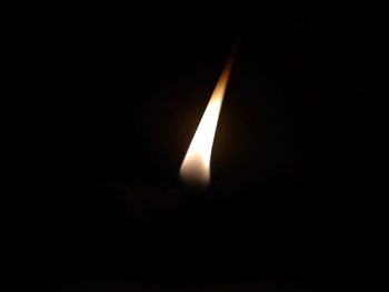 Close-up of lit candle in darkroom