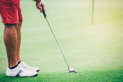 Low section of man playing golf course on field