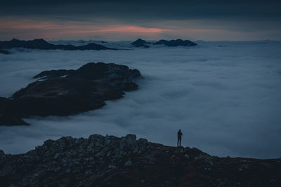 Man standing on rock against sky during sunset