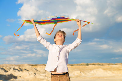 A teenage boy with smile launches a bright kite into the sky on a summer day.