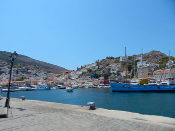 Boats moored at harbor against clear blue sky