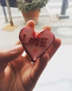Cropped image of hand holding heart shape decoration