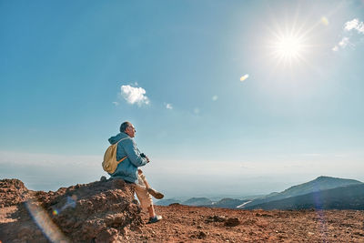 Rear view of man standing on mountain against sky