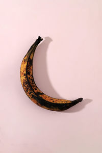Top view over ripe rotten banana on pink background