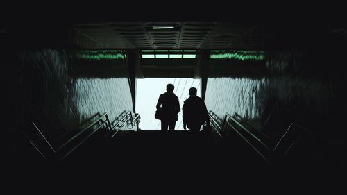 Rear view of silhouette people walking in underground stairs