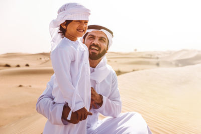 Smiling young man standing on land against sky