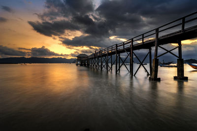 Bridge over sea against sky during sunset