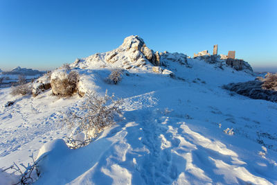 Scenic view of snow covered mountains against clear blue sky