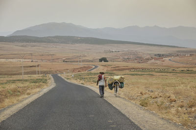 Rear view of people walking on road in desert