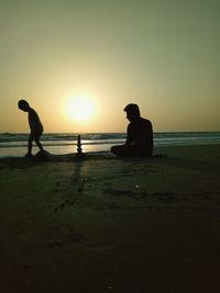 Silhouette of father and son at beach during sunset