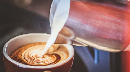 Close-up of milk pouring in coffee cup