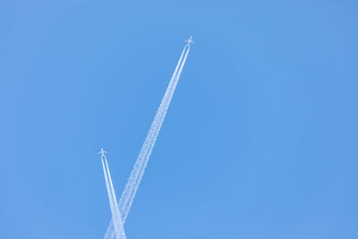 Low angle view of airplane flying against clear blue sky