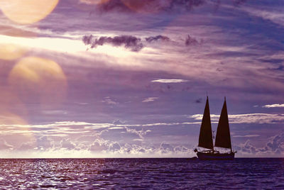 Silhouette sailboat sailing in sea against sky