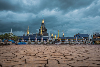 Temple by building against sky at dusk