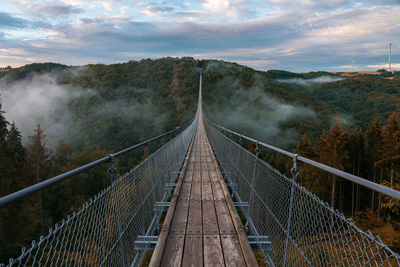 Footbridge over trees against sky