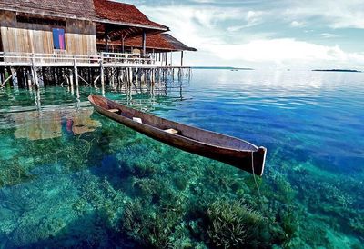 Stilt house by sea against sky