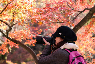 Man photographing with autumn tree