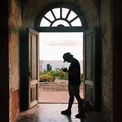 Side view full length of man standing at doorway