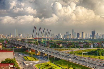 Bridge over river amidst buildings in city against sky