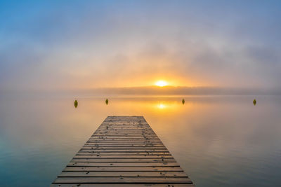 Pier over sea against sky during sunset