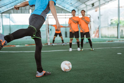 Low section of man playing soccer at park