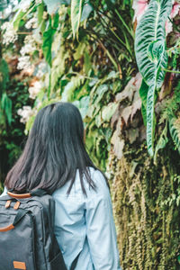 Rear view of woman standing amidst plants