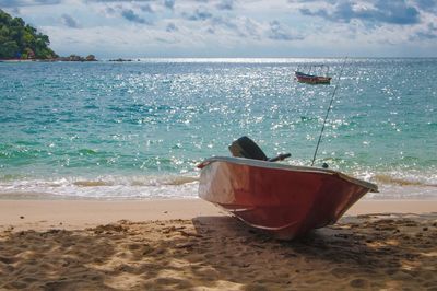 Boat moored on beach against sky