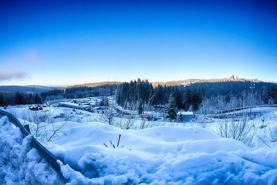 Snow covered landscape against blue sky