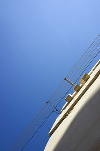 Low angle view of cables against clear blue sky