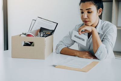 Businesswoman holding resignation letter sitting at desk in office