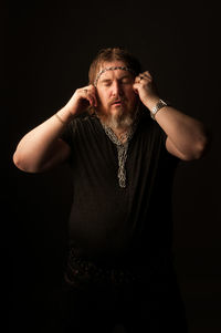 Portrait of mid adult man standing against black background