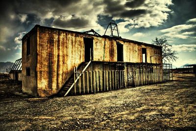 Abandoned building against cloudy sky