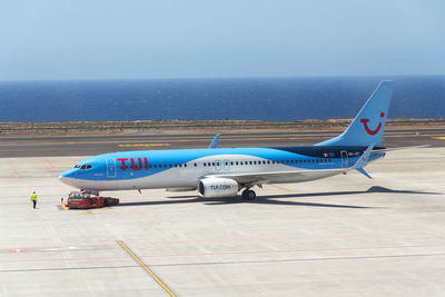 Airplane on airport runway against sky