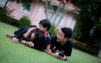 Rear view of friends looking at camera while sitting on grass