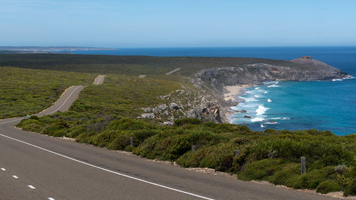 Scenic view of road by sea against sky