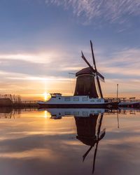 Traditional windmill against sky during sunset