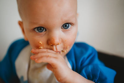 Close up of beautiful baby with blue eyes eating with his hands