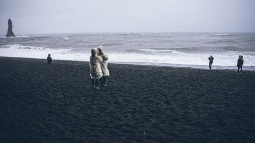 Rear view of people walking on beach