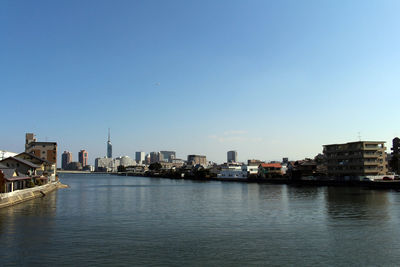 River and buildings against clear blue sky