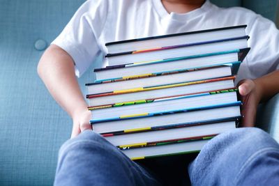 Kid showing his favourite book collection on sofa. self learning and distance education under covid.