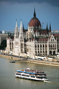 View of buildings by river against sky in city